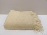a white pillow with a fringe on it on a white table