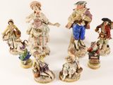 several figurines of people are standing in a circle on a white surface