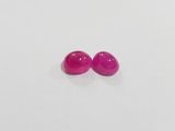 a pair of pink gems on a white surface