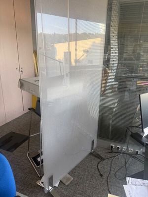 une cloison en verre au milieu d'une pièce, sur laquelle est posé un ordinateur