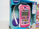 a pink toy phone in the box with a remote