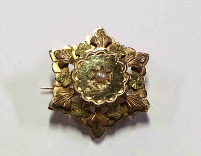 un gros plan d'une broche en or sertie d'une perle
