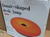 a box that has a donut shaped desk lamp on it