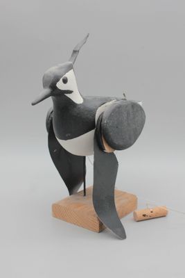 une image représentant un oiseau en noir et blanc posé sur un socle en bois