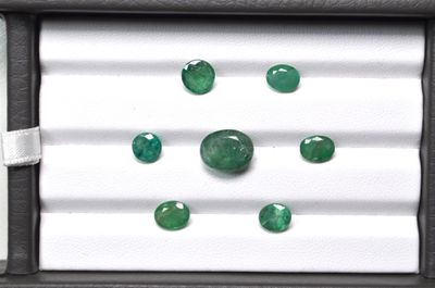 three emeralds in a box on a white surface