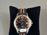 une montre orange et noire posée sur un oreiller noir