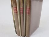 trois livres sont empilés sur une surface blanche