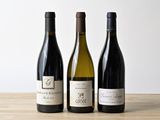 trois bouteilles de vin sont alignées sur une table en bois