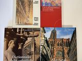 trois livres posés sur une table, avec une horloge et un clocher en arrière-plan