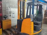 a forklift in a warehouse with pallets in the background