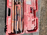 une mallette à outils rouge posée par terre, contenant des outils