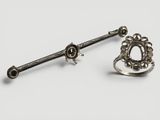 une paire de boucles d'oreilles en argent et une bague posées sur une surface blanche