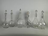 quatre bouteilles en verre transparent sont alignées sur une surface blanche