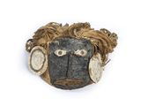 a wooden mask with a face on it on a white surface