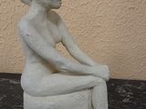 a statue of a woman sitting on a rock