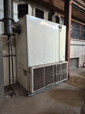 un grand réfrigérateur blanc dans un immeuble où il y a beaucoup de tuyaux