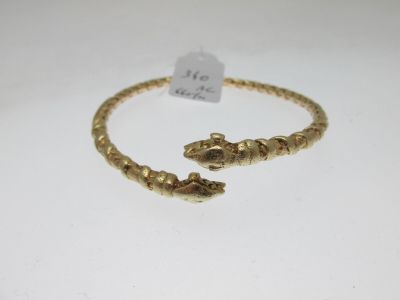 gros plan d'un bracelet en or sur une surface blanche