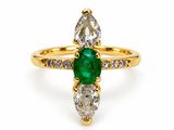 a close up of a ring with a green emerald and white diamonds