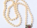 collier de perles orné d'un pendentif en forme de fleur rouge et blanche sur fond blanc
