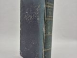 an old book sitting on top of a white table next to a white wall