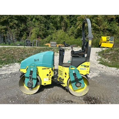 a yellow and blue road roller sitting on top of a gravel road