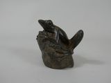 a statue of a frog sitting on top of a tree stump