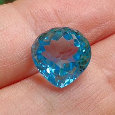 someone is holding a blue topaz stone in their hand