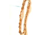 une photo d'un bracelet en or posé sur une surface blanche