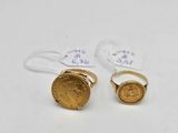 two gold rings with a coin on top of them on a white surface