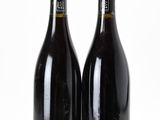 two bottles of wine sitting next to each other on a white surface