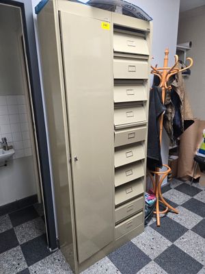 a tall metal cabinet with a bunch of clothes hanging on it