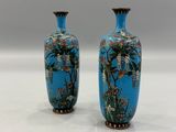 pair of blue vases with flowers on them sitting on a white surface