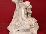 a white statue of a woman and a child on a red surface