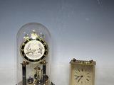 a small clock sitting under a glass dome next to a small clock