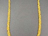 a close up of a gold necklace on a black surface