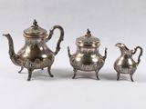 deux théières en argent et une cafetière posées sur une table