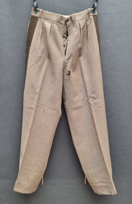 an old pair of pants hanging on a hanger on a wall