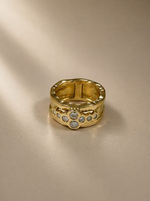 a close up of a gold ring with diamonds on a white surface