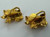 two gold tone frog charms on a white surface