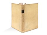 un vieux livre à la couverture dorée posé sur une surface blanche