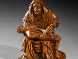 une photo représentant une statue en bois d'une femme assise sur un banc
