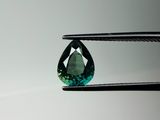 a close up of a green tourmaline gems being held by a pair of tongs