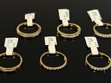 six gold rings with diamonds on them sitting on a black surface