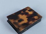 an image of a small tortoise shell box sitting on a white surface