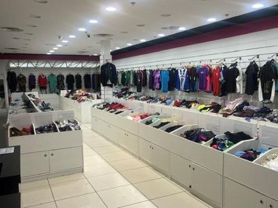 Dans un magasin de vêtements, des rangées de vêtements sont alignées le long du mur.
