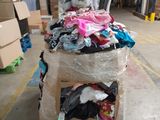 a cart full of clothes in a warehouse with a stuffed animal on top of it