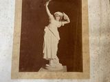 an old photograph of a statue of a woman holding a baseball bat