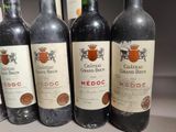six bottles of red wine are lined up on a table