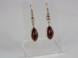 pair of silver and red glass earrings on a clear acrylic stand