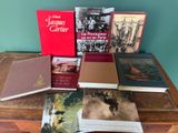 Plusieurs livres sont posés sur une table en bois devant un mur vert.